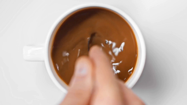 widok z góry człowieka mieszając kawę z łyżką na białym - Materiał filmowy, wideo