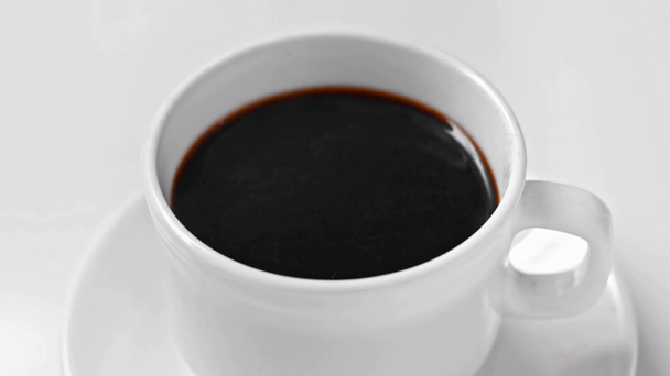 白で隔離されたソーサーにブラックコーヒーを飲み - 映像、動画