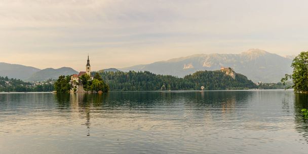 Küçük adadaki St. Marys Varsayım Kilisesi ile kan gölü. Kan, Slovenya, Avrupa. Arka planda dağlar ve vadiler.  - Fotoğraf, Görsel