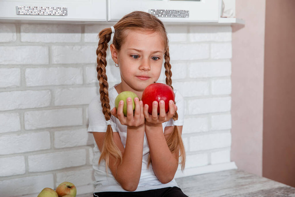 Cute little girl with apples in the kitchen - Zdjęcie, obraz