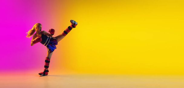 Little caucasian female kick boxer training on gradient background in neon light, active and expressive - Fotoğraf, Görsel