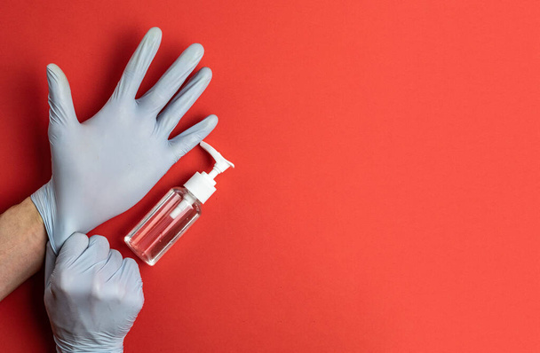 Choroby ochronne. Ręce Używanie medycznego żelu antybakteryjnego w rękawiczkach laboratoryjnych - sprzęt do ochrony przed wirusami na czerwonym tle. Czysty środek dezynfekujący w butelce pompy. Środki zapobiegawcze przeciwko koronawirusowi - Zdjęcie, obraz