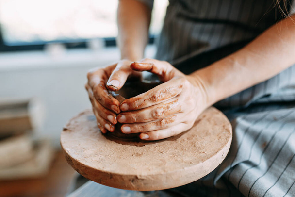Manos de una chica en una rueda Potters con barro. El proceso de creación de cerámica
. - Foto, imagen