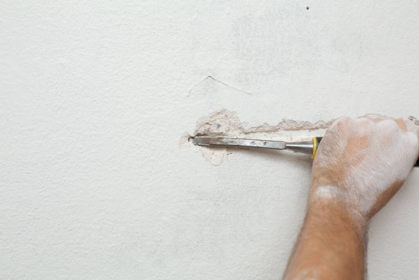 Repair of the premises. A man makes a ditch for laying cable into the wall. Laying electrical wiring in the wall - 写真・画像