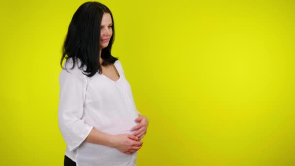 Young pregnant woman with is massaging belly, the child is pushing and moving - Кадры, видео