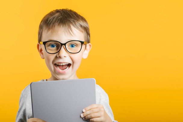 Happy child boy  holding a tablet ipade for your information on the blue background  - Zdjęcie, obraz