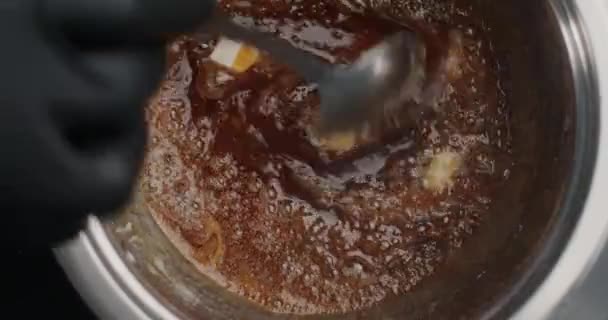 Tabletop slow motion video: confectioner in black gloves adds butter to the boiling melted sugar, chef makes hot caramel, cooking filling for cake, 4k 60fps Prores HQ 10 bit - Video, Çekim