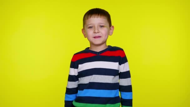 小さな子供の男の子はコピースペースと黄色の背景にカメラを見て - 映像、動画