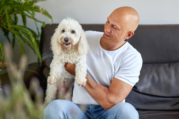 Hombre guapo con lindo perro en casa
 - Foto, Imagen