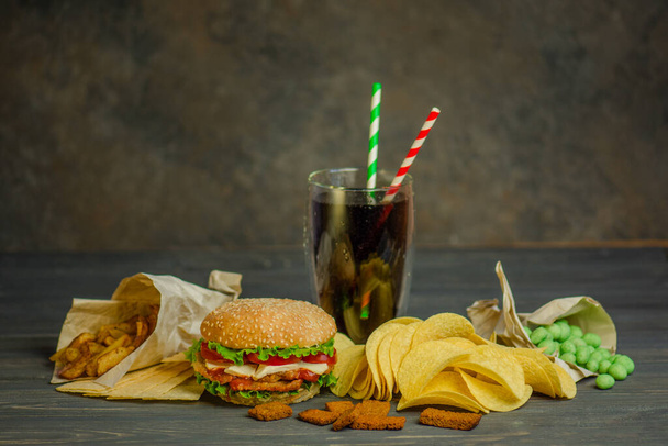 Уличная еда или фаст-фуд. Гамбургер, картошка фри и кола на столе с деревянным фоном. Нездоровый бургер с говядиной
. - Фото, изображение