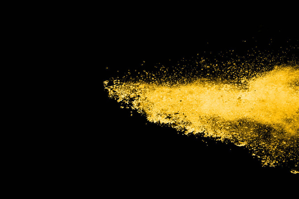 Bevries beweging van gele stof explosie geïsoleerd op zwarte achtergrond. - Foto, afbeelding