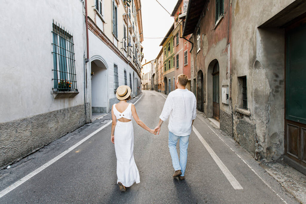 The couple walks on the asphalt. In the middle of old buildings. - Foto, imagen