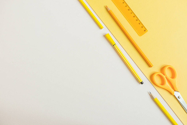 Okula dönüş kavramı. Okul kırtasiyesi düz: kalem, kalem, makas sarı ve gri zemin üzerinde. Turuncu ve sarı tonlarda. Kopyalama alanı. - Fotoğraf, Görsel