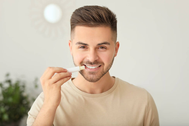Handsome young man with lip balm at home - Foto, Imagen