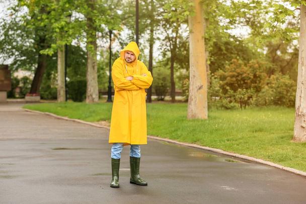 Displeased young man wearing raincoat outdoors - Photo, Image