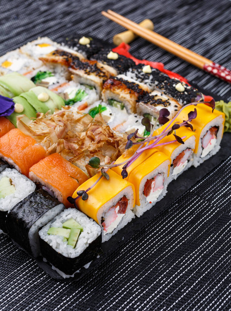 寿司は石板の上でレストランで日本料理を転がします。寿司ロールが近くに設置されています. - 写真・画像