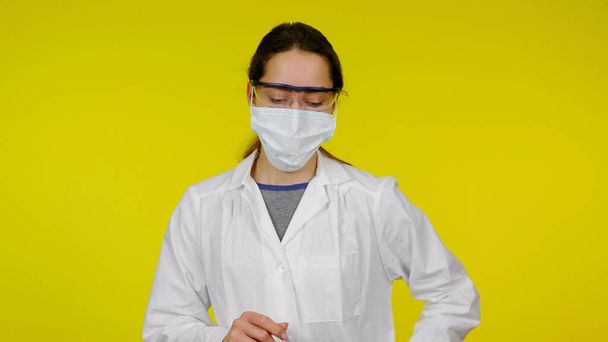 Fiatal orvos védő orvosi maszkban, szemüvegben és fehér köpenyben - Fotó, kép