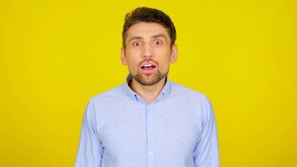 Hombre sorprendido en una camisa azul claro sobre un fondo amarillo con copyspace
 - Foto, Imagen