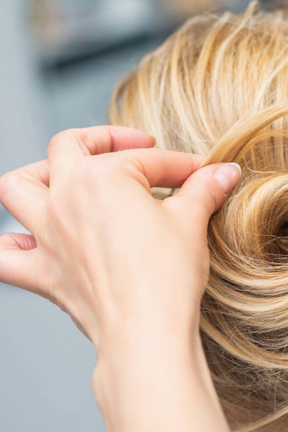 Close up vista posteriore del parrucchiere rendendo l'acconciatura per i capelli lunghi della donna bionda
. - Foto, immagini
