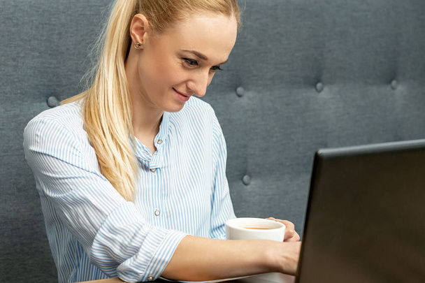 Młoda kobieta korzysta z laptopa podczas nauki online w biurze. - Zdjęcie, obraz
