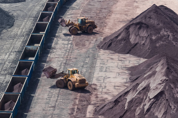 WHEEL LOADERS - Machines work on loading fossil minerals onto railway wagons - Photo, Image