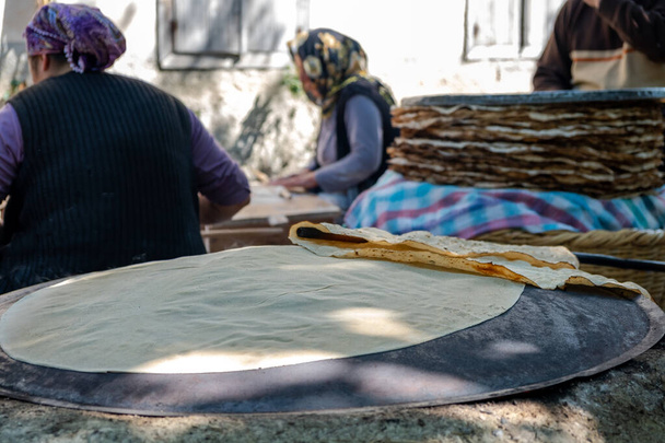 Traditioneel Turks brood. Ook bekend als "yufka ekmek", natuurlijk biologisch zelfgemaakt yufka brood. Vrouw kookt het handgemaakte brood op houtvuur. - Foto, afbeelding