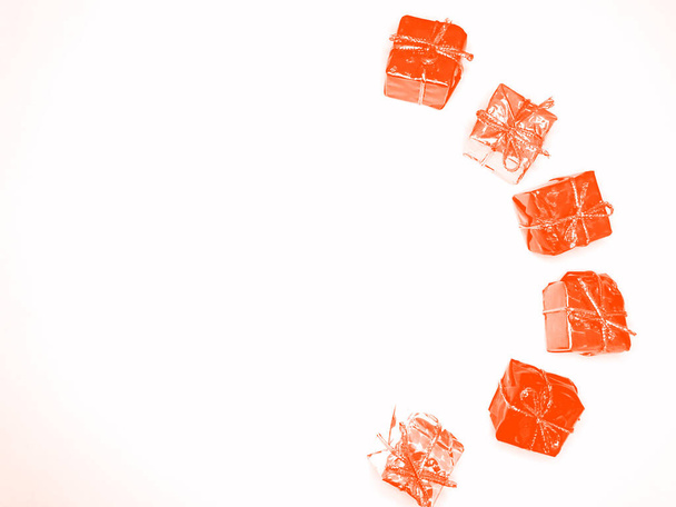 gros plan d'une pile de cadeaux enveloppés dans de beaux papiers et attachés avec des rubans de couleurs Lush Lava sur un fond blanc - Photo, image