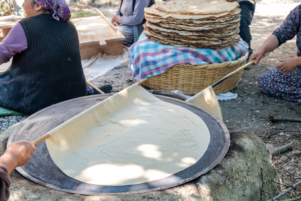 Traditioneel Turks brood. Ook bekend als "yufka ekmek", natuurlijk biologisch zelfgemaakt yufka brood. Vrouw kookt het handgemaakte brood op houtvuur. - Foto, afbeelding