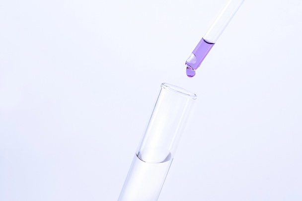 drop of liquid falls into a test tube on a gray background - Photo, Image