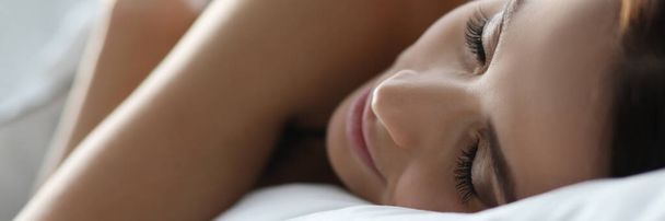 白い寝具の上で静かに寝ている若い女性 - 写真・画像