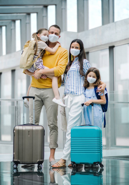 Family with two children going on holiday, wearing face masks at the airport. - Zdjęcie, obraz