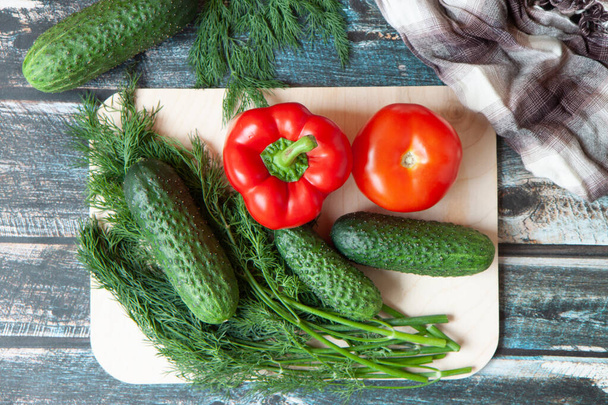 vegetables, Bulgarian peppers, dill, cucumbers on a light cutting Board, dark wooden background - Foto, Imagem