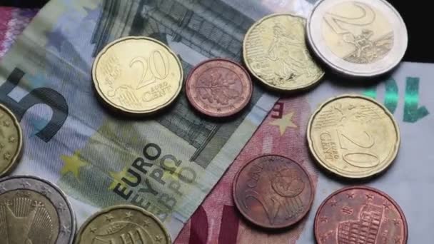 Euro banknotes and coins rotate as background. Shot looking down on a euro currency rotating. Coins are stacked on top of each other in different positions. Money concept. - Metraje, vídeo