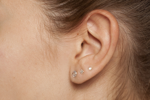 Női fül közelsége három fülbevalóval - Fotó, kép