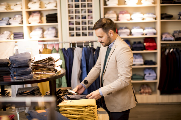 Hezký mladý muž kupovat kalhoty v obchodě - Fotografie, Obrázek