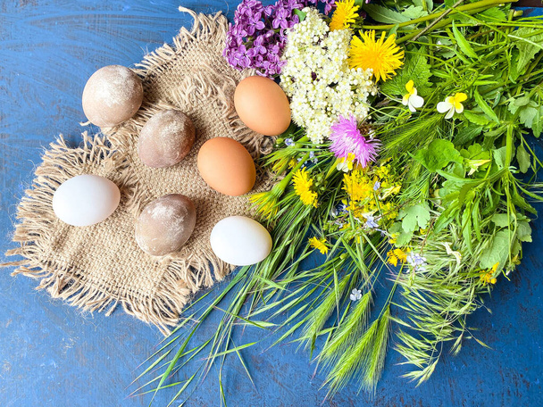 Festive Easter eggs with colorful wild flowers, on a background of blue abstract surface. - Photo, Image