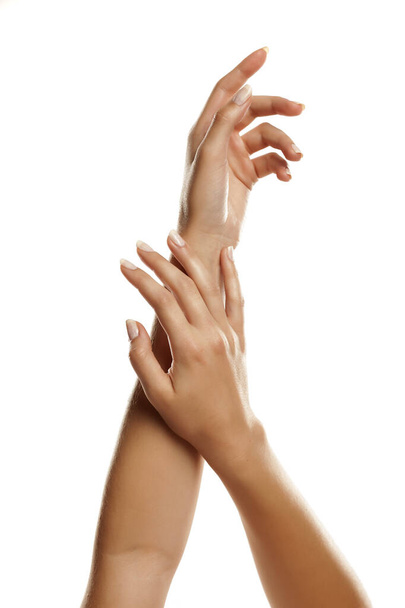 primer plano de las manos femeninas aplicando crema de manos sobre fondo blanco
 - Foto, Imagen