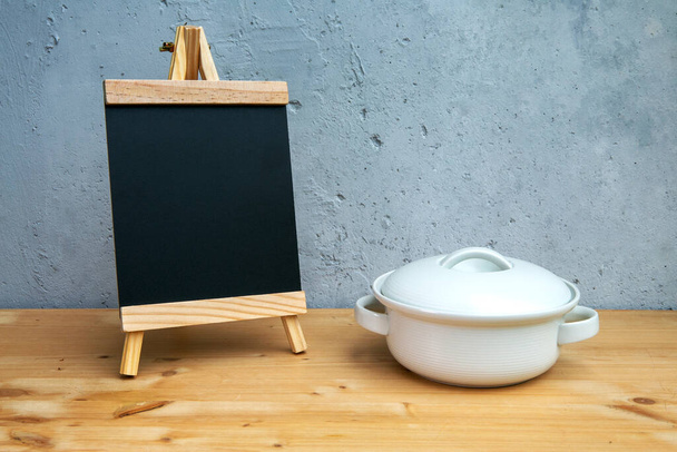 small blackboard with white pot on wooden table with grey background - Fotó, kép