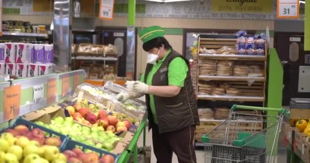 the seller in the mask lays out the fruits - Video