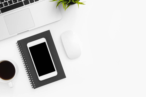 Az üres képernyős okostelefon a fehér íróasztal tetején van laptoppal és kellékekkel. Felülnézet fénymásoló felülettel, lapos fektetés. - Fotó, kép