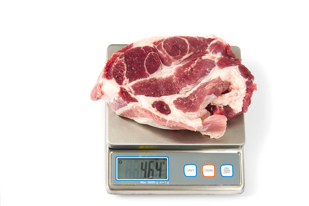 Filete de carne de cerdo crudo en la escala digital, sobre fondo blanco
. - Foto, imagen