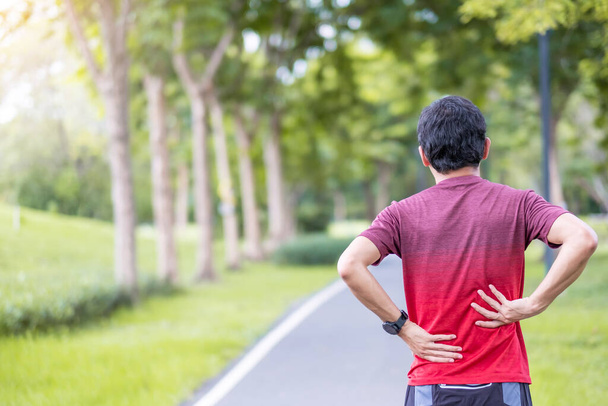 Jonge volwassen man met spierpijn tijdens het hardlopen. Runner man met rugpijn als gevolg van het Piriformis syndroom, lage rugpijn en spinale compressie. Sportblessures en medisch concept - Foto, afbeelding
