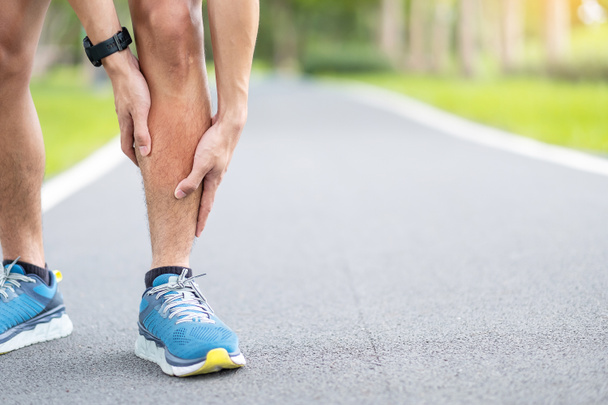 Homem adulto jovem com dor muscular durante a corrida. homem corredor com dor de perna devido a Shin Splints. Lesões desportivas e conceito médico - Foto, Imagem