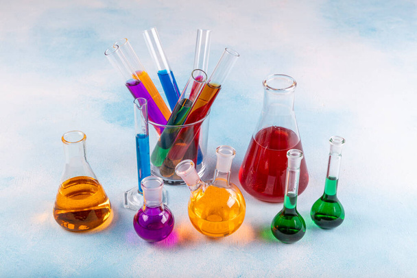 Verschillende laboratoriumglaswerk met kleurvloeistof. Chemisch glaswerk met gekleurde vloeistoffen in flessen. - Foto, afbeelding