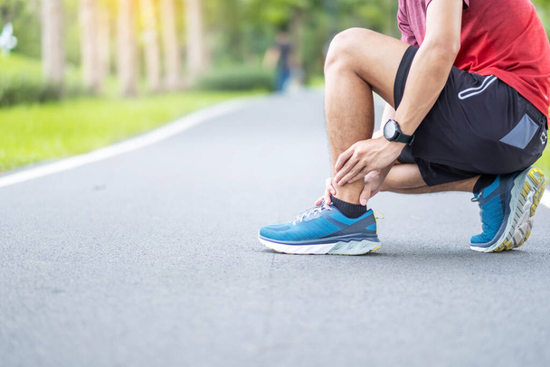 Junger erwachsener Rüde mit Muskelschmerzen beim Laufen. Läufer mit Beinschmerzen wegen einer Knöchelverstauchung oder Achillessehnenentzündung. Sportverletzungen und medizinisches Konzept - Foto, Bild