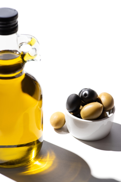 olive oil in bottle near green and black olives in bowl on white background - Fotografie, Obrázek