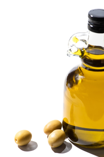 olive oil in bottle near green olives on white background - Valokuva, kuva