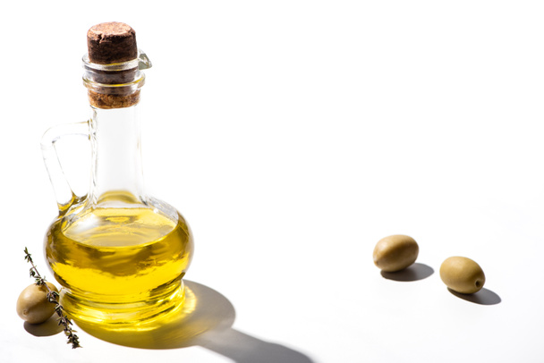 olive oil in jar near green olives with herb on white background - Foto, Imagen