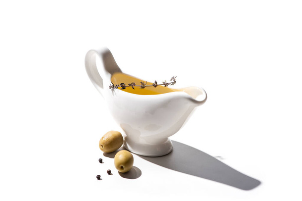 olive oil in sauce boat near green olives and black pepper on white background - Foto, Bild