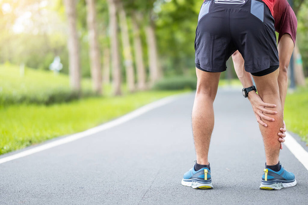 走っている間に彼の筋肉痛の若い大人の男性。カーフ・マッスル・プルのせいで足の痛みを持つランナーの男。スポーツ傷害と医療の概念 - 写真・画像